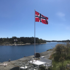 bilde av et norsk flagg på en flaggstang i norsk skjærgrad.