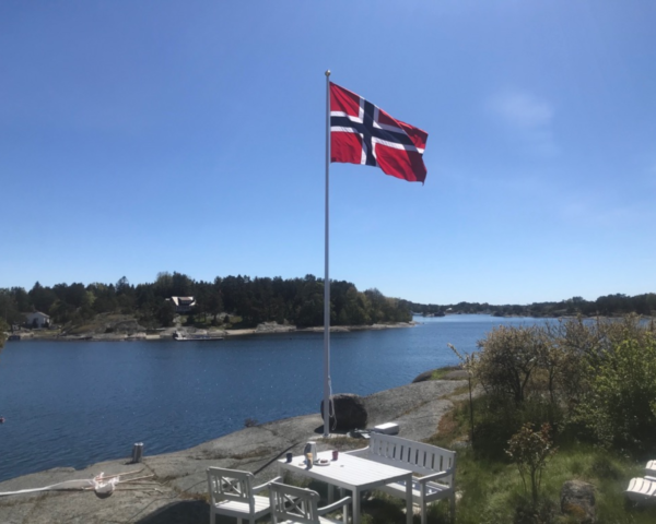 bilde av et norsk flagg på en flaggstang i norsk skjærgrad.