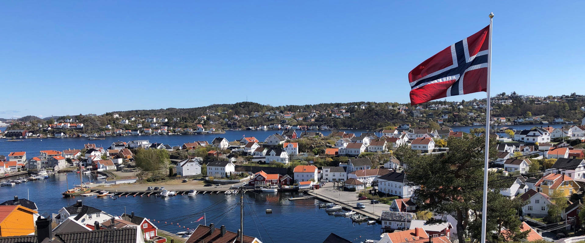 flaggstang med det norske flagg ved fjorden